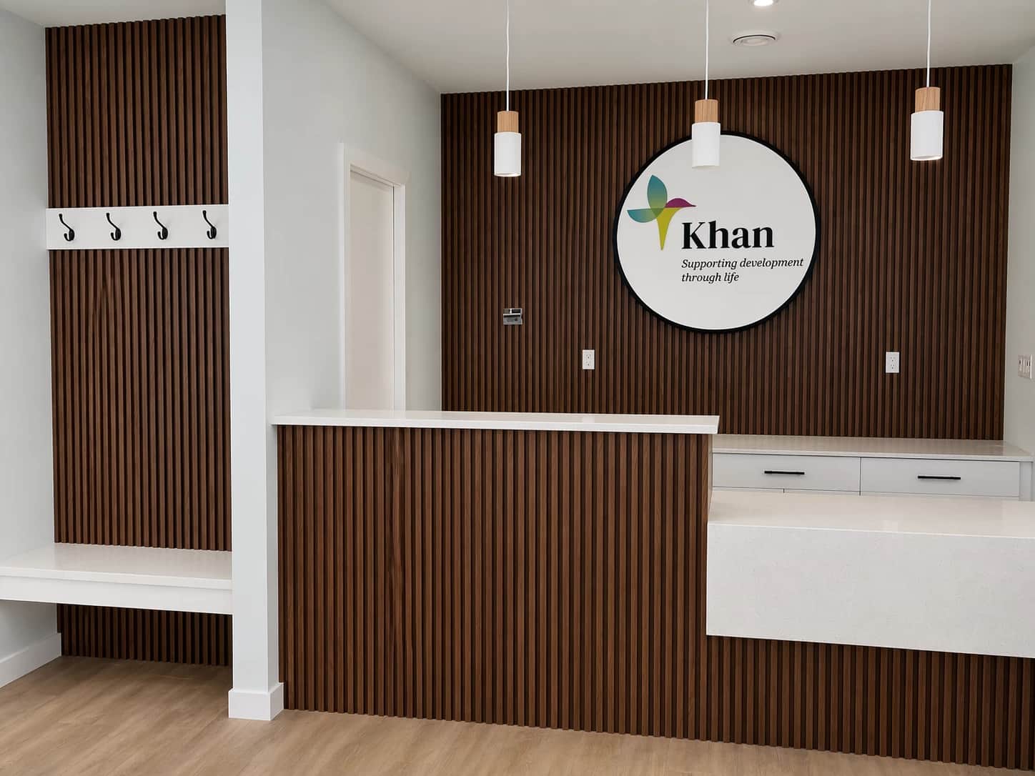Commercial reception desk with slatted wood wall and Khan signage